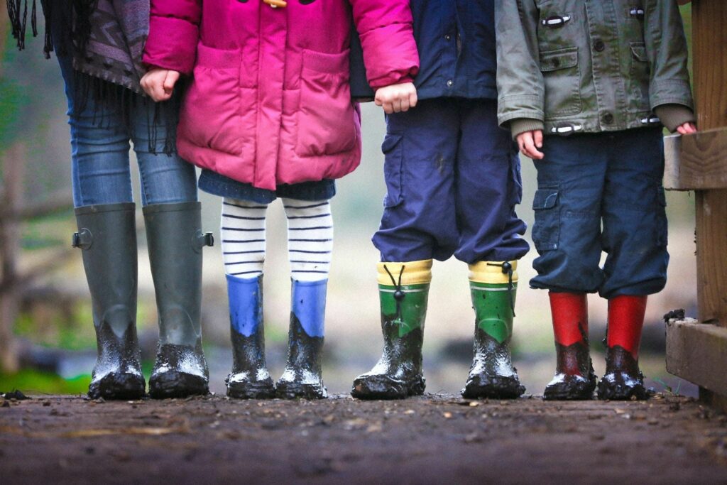 Jambes d'enfants avec bottes colorées symbolisant la préparation de l'avenir financier des mineurs